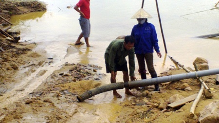 Một cát tặc chuẩn bị ống hút để bơm cát từ thuyền lên xe