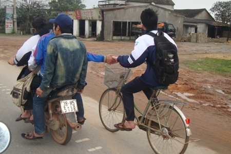 Một nhóm học sinh đi xe máy chở 4, không đội mũ bảo hiểm còn kéo theo xe đạp