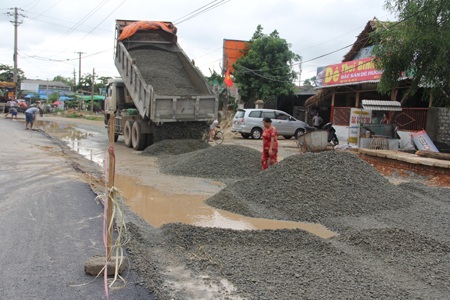 Nhà thầu cho máy gạt bê tông phủ lên nền đường sũng nước.  