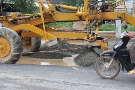 Nhà thầu cho máy gạt bê tông phủ lên nền đường sũng nước.  