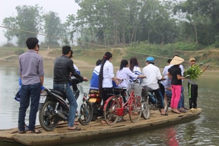 15 người chen chúc trên con đò nhỏ, di chuyển sang bờ bên kia bằng cách đu dây.