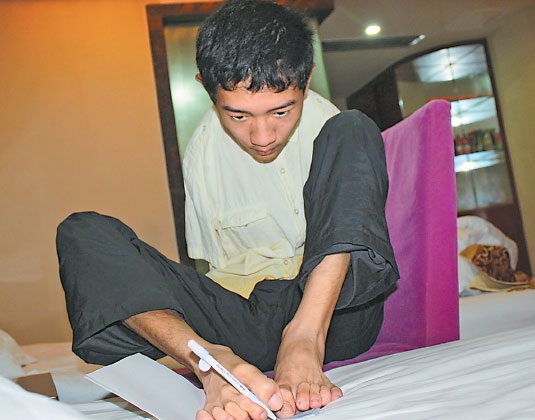 Tân sinh viên không tay truyền cảm hứng cho giới trẻ - 1 Peng Chao viết bằng chân. (Ảnh: China Daily)