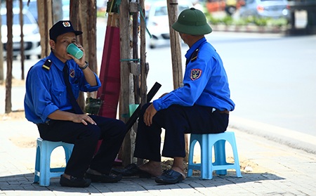 Chui gọn trong chiếc ô nhỏ là giải pháp tình thế của hai người bảo vệ trên đường Nguyễn Chí Thanh