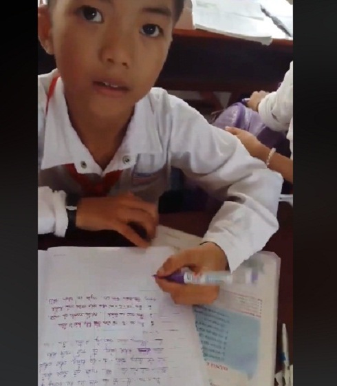 Cậu bé 9 tuổi ở Kiên Giang xoay ngược vở, dùng tay trái viết chữ siêu đẹp - 1 Cậu học sinh với khả năng viết chữ đặc biệt. (Ảnh cắt từ clip)