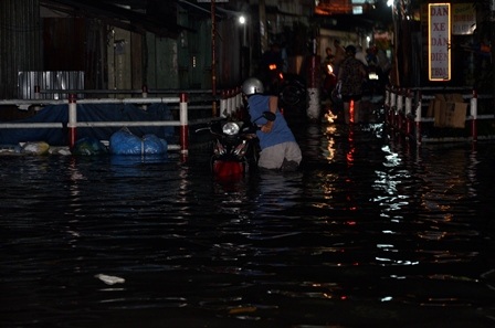 Một người đàn ông dắt xe quay lại chọn lối đi khác vì phía trước ngập quá sâu
