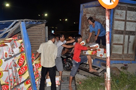 Công nhân bốc dỡ số bia trên xe tải bị lật sang xe khác.