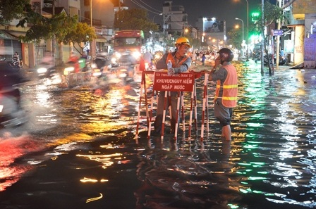 Các công nhân đứng giữa đường để cảnh báo khu vực ngập sâu cho người dân được biết