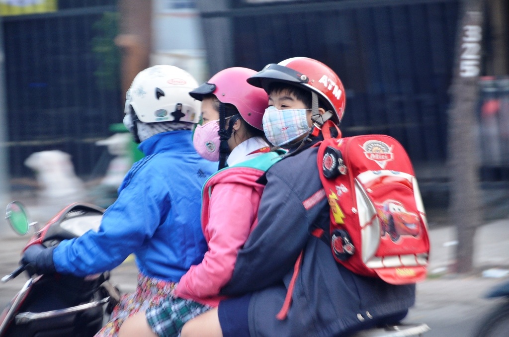 Một người phụ nữ dừng xe quấn thêm khăn trên đường