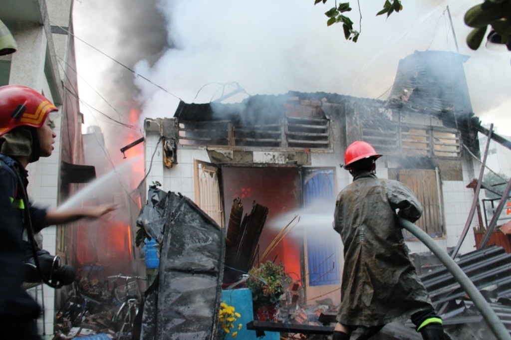 Lính cứu hỏa khống chế ngọn lửa đang bao trùm căn nhà ở quận Thủ Đức vào sáng mùng 1 Tết.