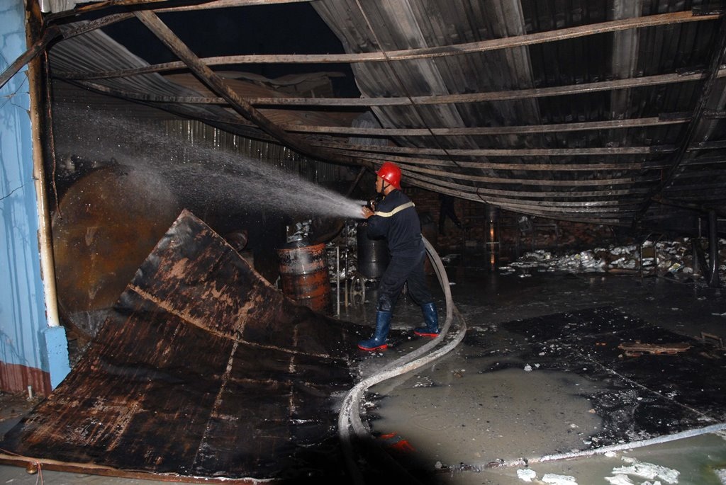 Cháy lớn kho chứa cồn nằm gần chợ - 1 Lính cứu hỏa phun nước tránh đám cháy bùng phát trở lại