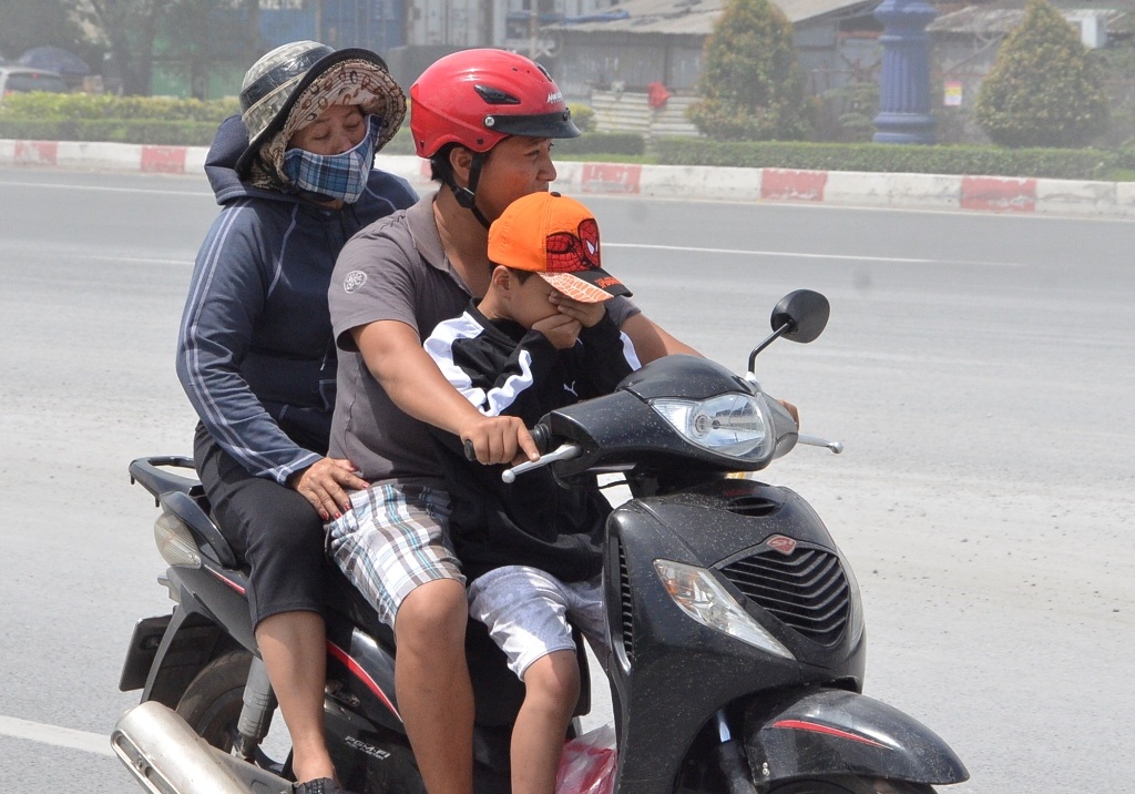 Một em nhỏ phải bịt cả mặt khi được bố chở qua cung đường bụi