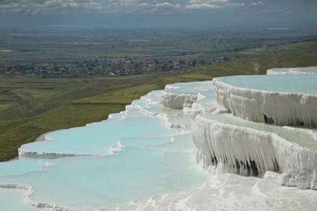 
Pamukkale hay còn được biết đến với cái tên “Lâu đài bông”, được tạo thành bởi calcium carbonate đông cứng lại theo thời gian, tạo nên một vùng núi đá vôi đẹp như truyện cổ tích. Du khách tới Pamukkale nên chuẩn bị sẵn đồ bơi bởi vì bạn sẽ không thể chối từ được việc ngâm mình trong làn nước mát với màu xanh như ngọc bích với nhiệt độ dao động từ 35oC đến 100oC.
