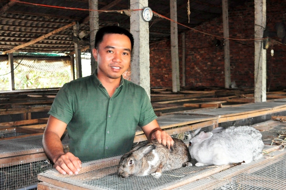 Chàng trai trẻ kiếm trăm triệu đồng mỗi năm từ nghề nuôi thỏ - 1 Anh Võ Thành Nghĩa với đàn thỏ của mình