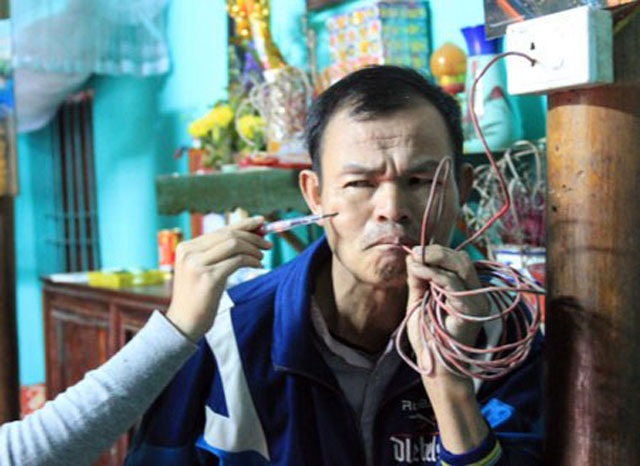 5 “dị nhân” có khả năng kỳ lạ nhất Việt Nam - 3 Ông Dương Đình Thắng ngậm dây diện rồi dùng bút thử điện gí vào người. Kết quả: Bút thử điện sáng đèn.