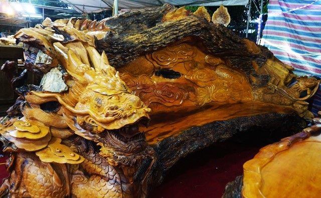 Chiêm ngưỡng bộ bàn ghế “tứ linh” bằng gỗ trai nghìn năm giá gần 3 tỷ đồng - 3 Nổi bật là chiếc ghế dài được chạm khắc thành hình con rồng dáng uy nghi nhưng đang uốn lượn hết sức mềm mại. bộ bàn ghế này được làm từ gốc rễ của cây gỗ trai, có tuổi đời khoảng gần 1000 năm, mua từ một tỉnh Tây Nguyên về.