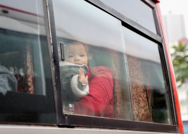 
Em bé ngoái nhìn ra ngoài cửa xe khách sau khi cả gia đình khá vất vả mới tìm được xe về quê.
