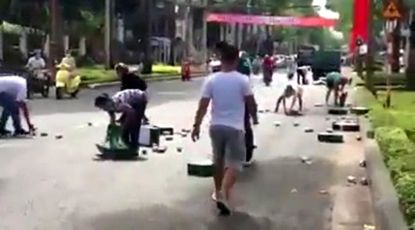 Hàng trăm lon bia lăn xuống đường, người dân chung tay nhặt giúp - 1 Người dân nhặt bia giúp tài xế -Ảnh cắt từ clip.