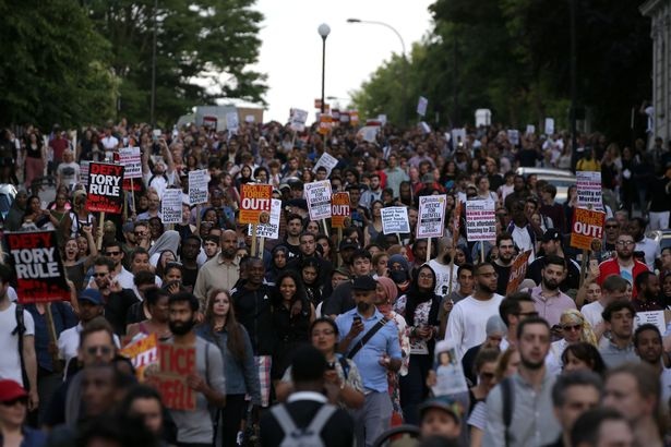 Đám đông hô vang những khẩu hiệu như: “Bà May phải rời đi”, “Công bằng cho Grenfell” hay “Máu vấy trên bàn tay của các người”. Các nhà tổ chức biểu tình ở London ước tính có khoảng 1.400 người tham gia, buộc cảnh sát phải huy động lực lượng để đảm bảo trật tự. (Ảnh: PA)