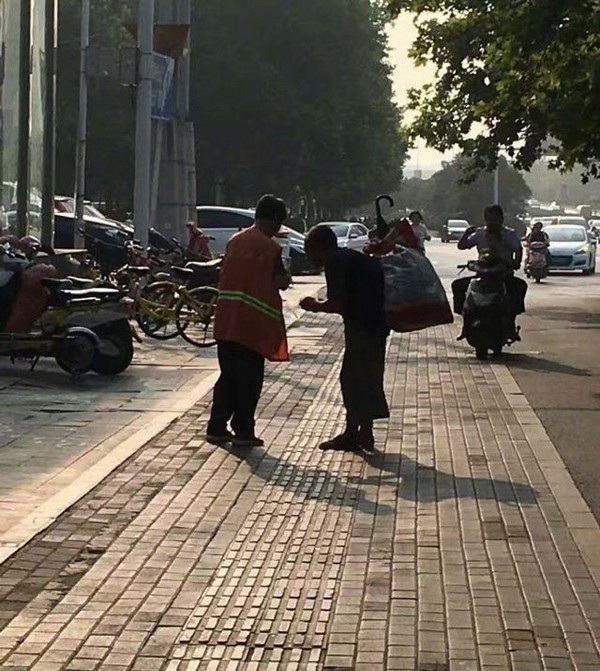Hình ảnh người quét rác chia bữa ăn cho người ăn xin mù khiến cộng đồng mạng cảm động - 1 Người phụ nữ lao công đang chia sẻ bữa ăn và tự tay bóc trứng luộc cho người ăn xin mù lòa