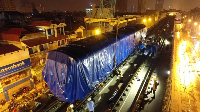 Sau nhiều giờ loay hoay, vào khoảng 2h45 ngày 21/2, chiếc cẩu bánh xích Kobelco CKS2500 (cần cẩu loại 250 tấn) đã đặt thành công toa tàu đầu tiên lên ray đường sắt Cát Linh - Hà Đông. (Ảnh: Mạnh Thắng)