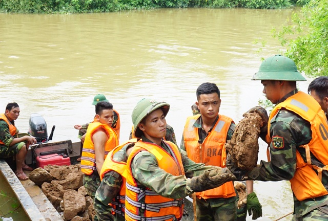 Vật lộn trong lũ chèn đá hộc, đóng cọc gia cố chân đê - 4 Nền đê yếu, đá hộc được tập kết phía bên kia bờ sông để tăng bo bằng thuyền sang khu vực bị sạt lở