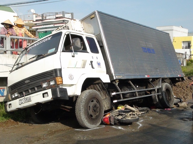 Xe tải tuột dốc cầu tông 2 xe máy, cháu bé 6 tuổi tử vong - 2 Một chiếc xe máy bị cuốn dưới gầm xe tải. Vụ tai nạn làm một em nhỏ 6 tuổi tử vong tại chỗ. (Ảnh: P.X)