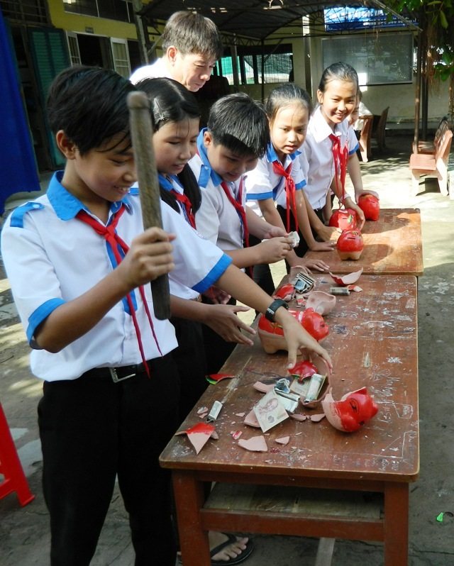 Học sinh khui heo đất tiết kiệm khuyến học - 2 Đập heo đất tại chỗ trước sự chứng kiến của lãnh đạo Hội Khuyến học, thầy cô giáo.