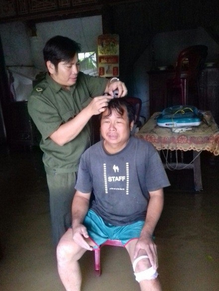 Người ôm chặt bè cá trôi trong lũ: “Cứu tài sản duy nhất của gia đình” - 1 Ông Hoàng Dũng đang được Trưởng Công an xã Quảng Phú sơ cứu vết thương ở đầu và chân