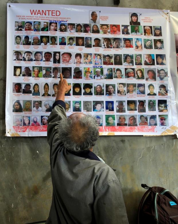 40 phần tử khủng bố nước ngoài tràn vào Philippines - 3 Cuộc xung đột tại Marawi tính đến nay đã bước sang tháng thứ 2. Theo thống kê mới nhất của giới chức Philippines, 280 tay súng khủng bố đã bị tiêu diệt kể từ khi cuộc xung đột bắt đầu hôm 23/5. Trong ảnh: Người dân Philippines chỉ vào ảnh của một thành viên trong nhóm Maute - nhóm phiến quân tấn công thành phố Marawi hôm 23/5.