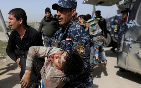 Gây thiệt hại dân sự lớn, Mỹ đang "lạc lối" ở Mosul, Iraq? - 1 Cảnh sát Liên bang Iraq trợ giúp một người dân Mosul bị thương sau các cuộc giao tranh. (Ảnh: Reuters)