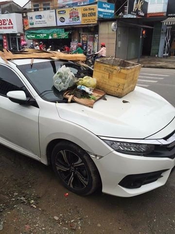 Ô tô đậu trước lối vào nhà dân bị đổ rác đầy nắp ca pô - 1
Chiếc xe ô tô bị vứt rác đầy trên đầu xe