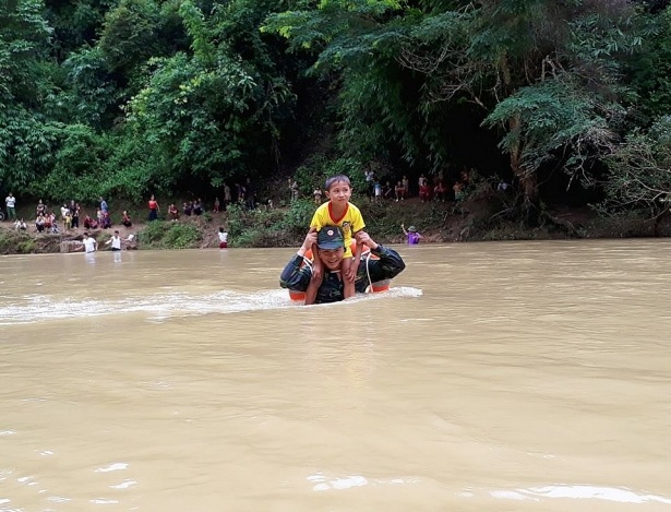 Bộ đội biên phòng kiệu trẻ em băng suối sâu đến trường - 1 Cán bộ biên phòng và nụ cười trên môi khi kiệu các em học sinh vượt sông. (Ảnh: BĐBP Điện Biên)