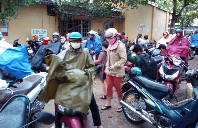 Sau bão số 16, học sinh trở lại học đầy đủ, nghiêm túc - 1 Phụ huynh ở Sóc Trăng đội mưa đưa con đến trường học sáng ngày 27/12.