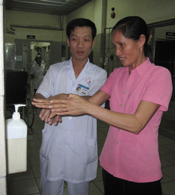 Nhiều ca bệnh bác sĩ tốn công sức vẫn không qua khỏi vì nhiễm khuẩn bệnh viện - 1 Nhân viên y tế hướng dẫn người nhà bệnh nhân rửa tay với dung dịch sát khuẩn trước khi chăm sóc người bệnh. Ảnh: H.Hải
