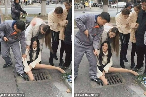 Vừa đi vừa dùng điện thoại, cô gái xinh đẹp lọt chân xuống cống - 1 Những người đi đường đang cố gắng giải thoát cô gái bị kẹt chân dưới cống