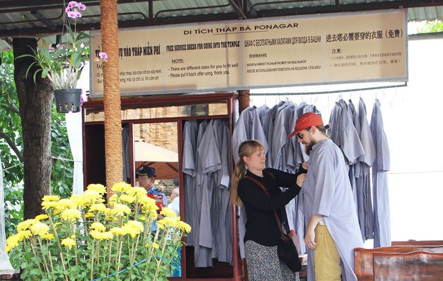 Áo choàng chống “nạn” hở hang: Cần phải thẩm mỹ và sạch sẽ - 2 Du khách nước ngoài hào hứng khoác áo dài khi vào tham quan Tháp bà Ponagar ở Nha Trang. Ảnh: D.T