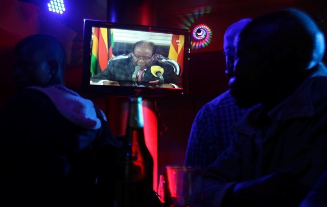 Tương lai nào cho Zimbabwe sau khi Tổng thống 93 tuổi từ chức? - 3 Người dân Zimbabwe theo dõi bài phát biểu của Tổng thống Mugabe sau khi ông bị quân đội quản thúc (Ảnh: Reuters)