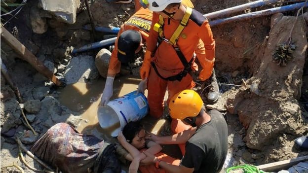 Phi công Indonesia kể lại phút cất cánh ngay khi động đất/sóng thần ập tới - 4 Nhân viên cứu hộ đưa một nạn nhân ra khỏi bùn lầy (Ảnh: Reuters)