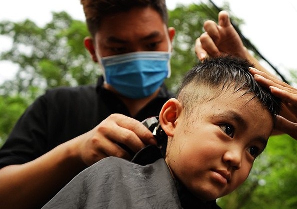 Soi đèn hớt tóc bên vỉa hè... nghĩa trang Bình Hưng Hòa - 13 Cháu ngoại bà Mai đang được phục vụ với vẻ mặt rất thích thú