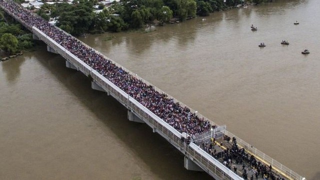 Tổng thống Trump ký lệnh đối phó dòng người di cư đổ về Mỹ - 1 Đoàn di dân tới Mỹ chen chúc qua một cây cầu. (Ảnh: AFP)