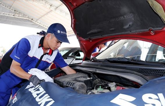 Kỹ thuật viên Suzuki kiểm tra động cơ cho xe Swift tại sự kiện.