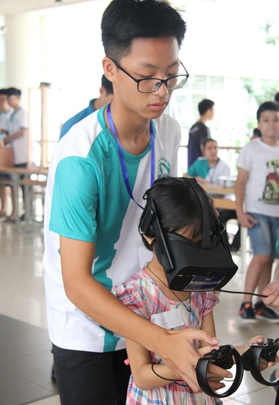 Học sinh Hà Nội thích thú trải nghiệm công nghệ 4.0 tại GART Expo 2018 - 2 Thành viên CLB GreenAms 6520 hướng dẫn các học sinh Hà Nội trải nghiệm kính thực tế ảo VR.