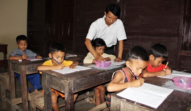 Những người thầy “gieo chữ” trên dãy Trường Sơn - 3 Thầy Trí hướng dẫn cho học sinh Tà Păng viết chữ.