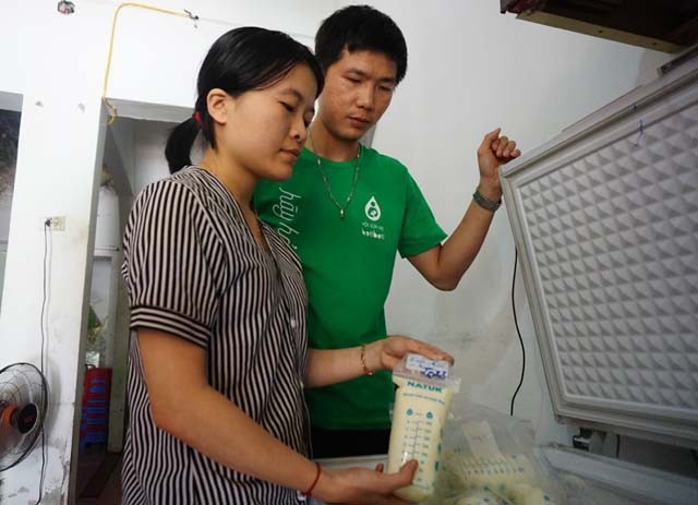 Vợ chồng chị Ngọc bên tủ sữa miễn phí của mình.