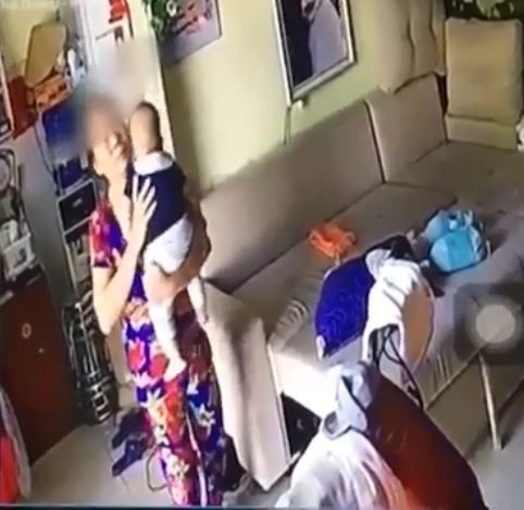 Giúp việc rung lắc, nhổ nước bọt vào miệng cháu bé: Sao người ta ác thế? - 1 Trong clip chưa đầy 1 phút được đăng tải, người phụ nữ trung tuổi liên tục có hành vi rung lắc mạnh cháu bé. Ảnh cắt từ clip
