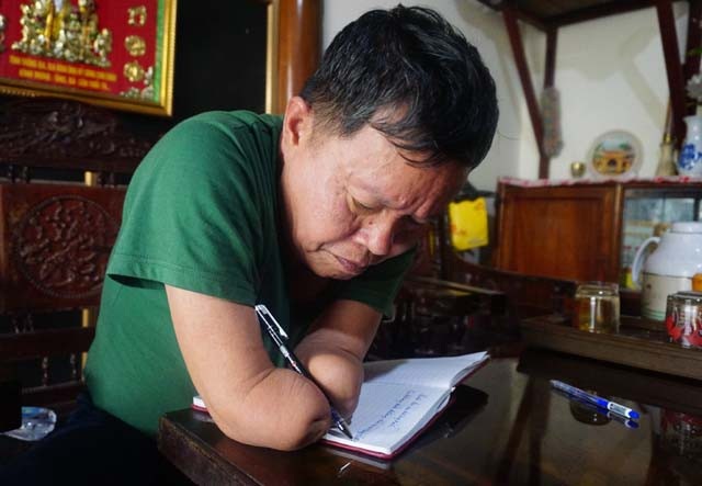 Người thương binh tự làm mọi việc từ đôi tay không còn bàn tay - 7 Không còn bàn tay để cầm bút, ông bắt hai mẩu thịt còn lại của hai cánh tay tuân theo sự điều khiển của mình. Với cách cầm bút này, ông Linh hầu như phải học lại cách viết chữ...