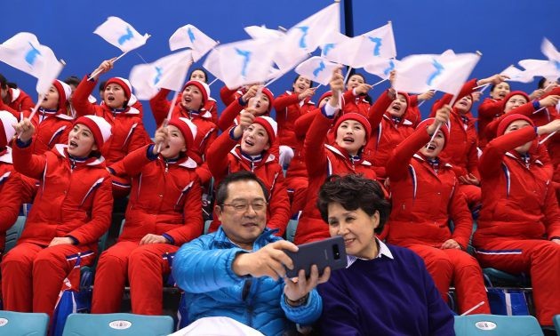 Hai người Hàn Quốc chụp ảnh cùng đội cổ vũ Triều Tiên trong trận thi đấu khúc côn cầu của Thế vận hội (Ảnh: Reuters)