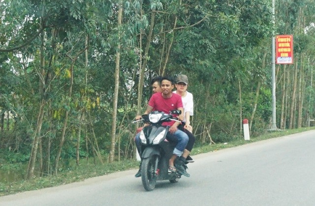 Cả ba người ngồi trên xe mô tô không đội mũ bảo hiểm (ảnh chụp trên đường Nguyễn Văn Trỗi, huyện Hưng Nguyên, Nghệ An)