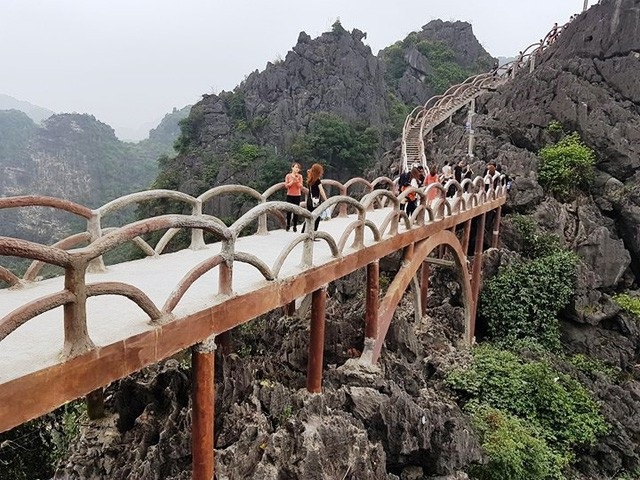 Đại diện UNESCO tại Việt Nam nói gì về công trình vi phạm ở Tràng An? - 1 Không chỉ những bậc, lan can cầu thang, doanh nghiệp còn làm một chiếc cầu kiên cố bắc từ đỉnh núi này qua đỉnh núi khác để làm đường đi cho khách. Bước đầu đưa vào khai thác, Công ty CP Du lịch Tràng An vẫn chưa thu vé nên lượng người đổ về đây như trảy hội, có ngày lượng khách lên đến gần 20.000 người. Người dân chen chúc nhau trên đường lên núi, ai dám chắc tai nạn không xảy ra? Khi đó ai sẽ là người chịu trách nhiệm? (Ảnh: Thái Bá).