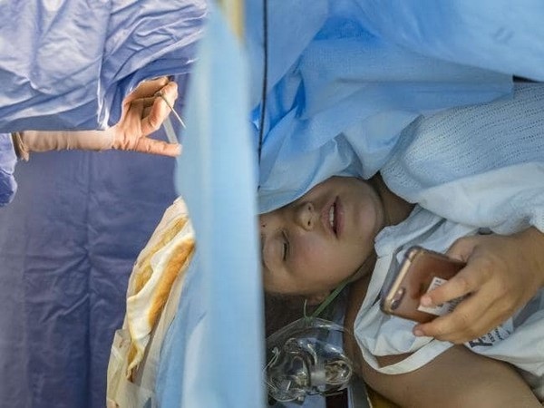 Cô gái vẫn bình thản sử dụng smartphone trong lúc đang phẫu thuật não - 1 Jess Banik đang sử dụng điện thoại trong khi các bác sĩ đang tiến hành ca phẫu thuật não cho cô